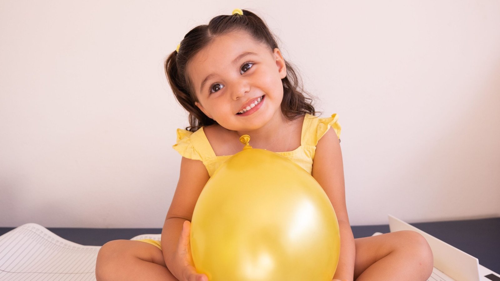 A happy girl holding a yellow balloon