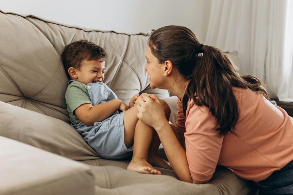 Mother sitting on a couch talking calmly with her young son about boundaries