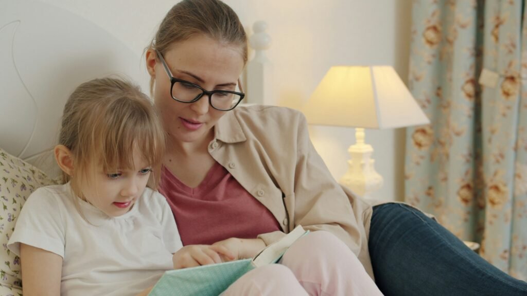 Mother reading a book to her daughter in bed, reconnecting after a hard day